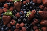 A collection of fresh berries, including strawberries, raspberries, blackberries, and blueberries, creating a vibrant and appetizing assortment with varied textures and glossy surfaces.