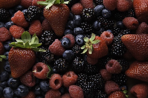 A collection of fresh berries, including strawberries, raspberries, blackberries, and blueberries, creating a vibrant and appetizing assortment with varied textures and glossy surfaces.