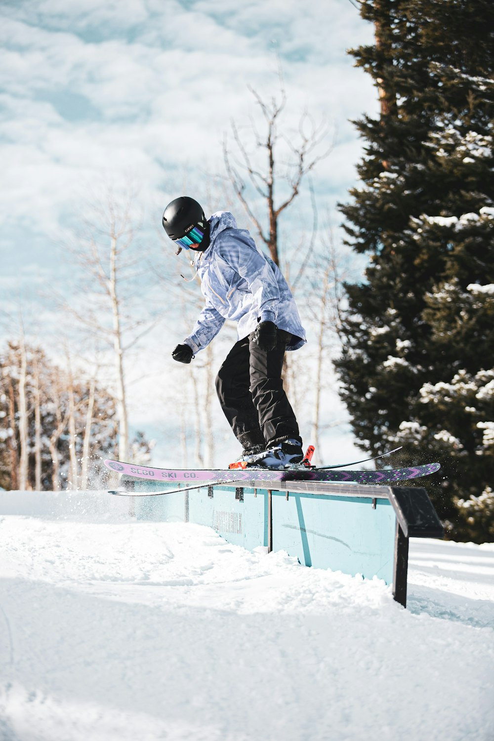 Uomo in giacca blu e pantaloni neri che cavalcano sullo snowboard durante il giorno
