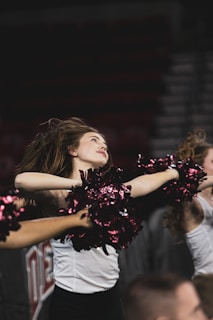 Cheerleaders mid-jump at a vibrant college sports event