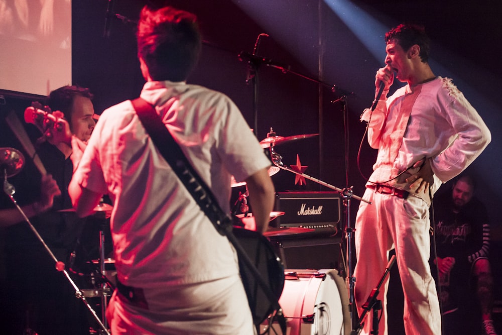 man in white dress shirt singing on stage