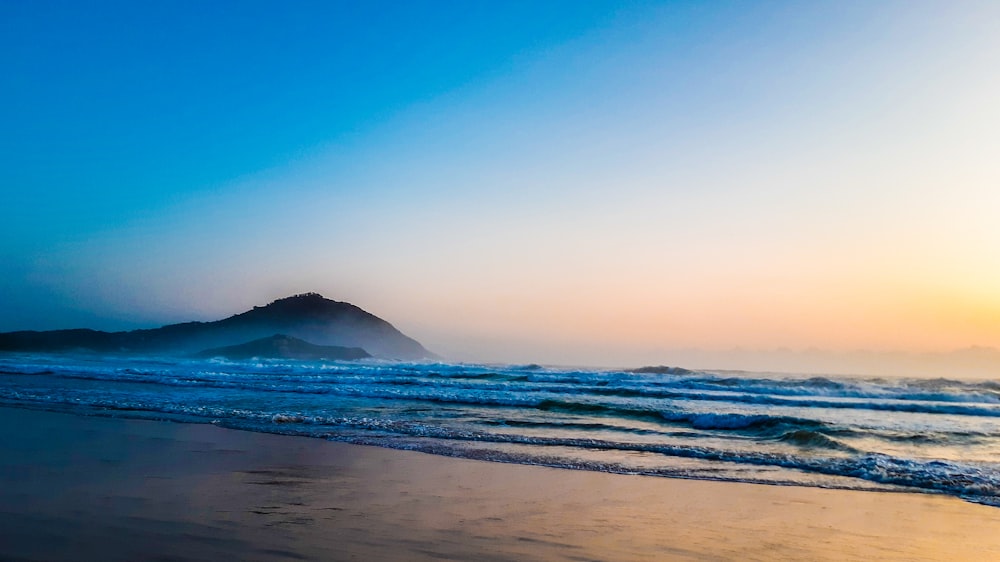 sea waves crashing on shore during sunset