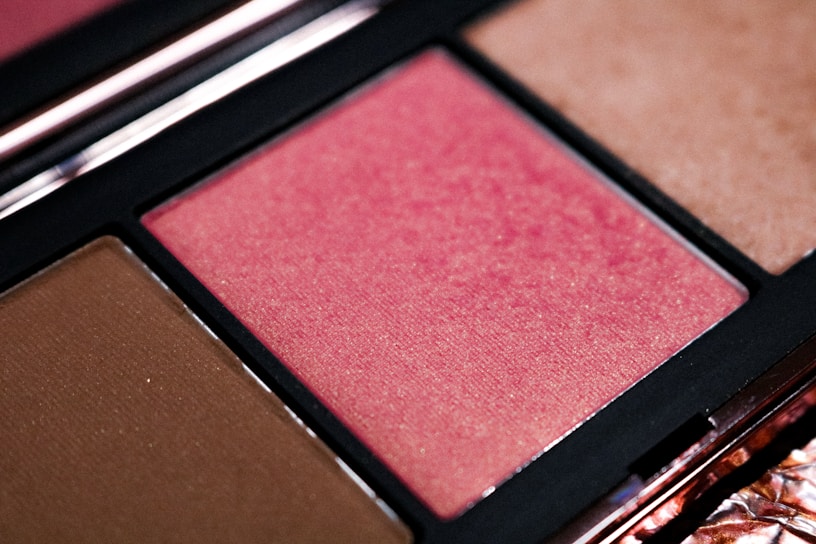 A close-up of a luxurious makeup palette with rich, vibrant colors arranged elegantly on a soft, cream background.