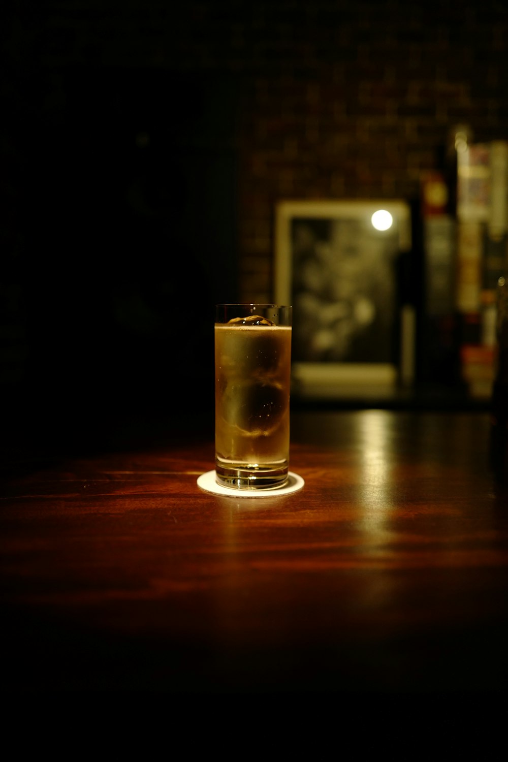 clear drinking glass with brown liquid on brown wooden table