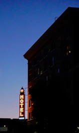 Evening shot of the hotel exterior lit warmly against a sunset sky.