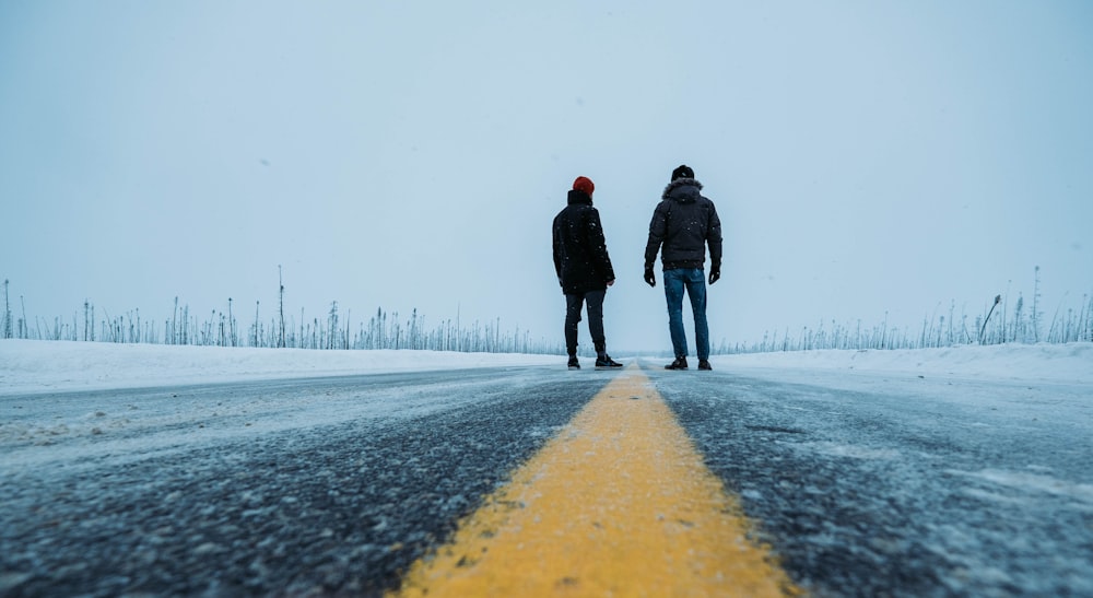 homem e mulher que caminham na estrada coberta de neve durante o dia