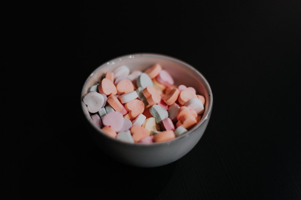 white and brown round candies in white ceramic bowl