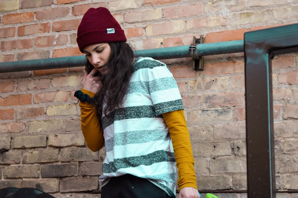 woman in yellow and white striped long sleeve shirt and black skirt sitting on brown wooden