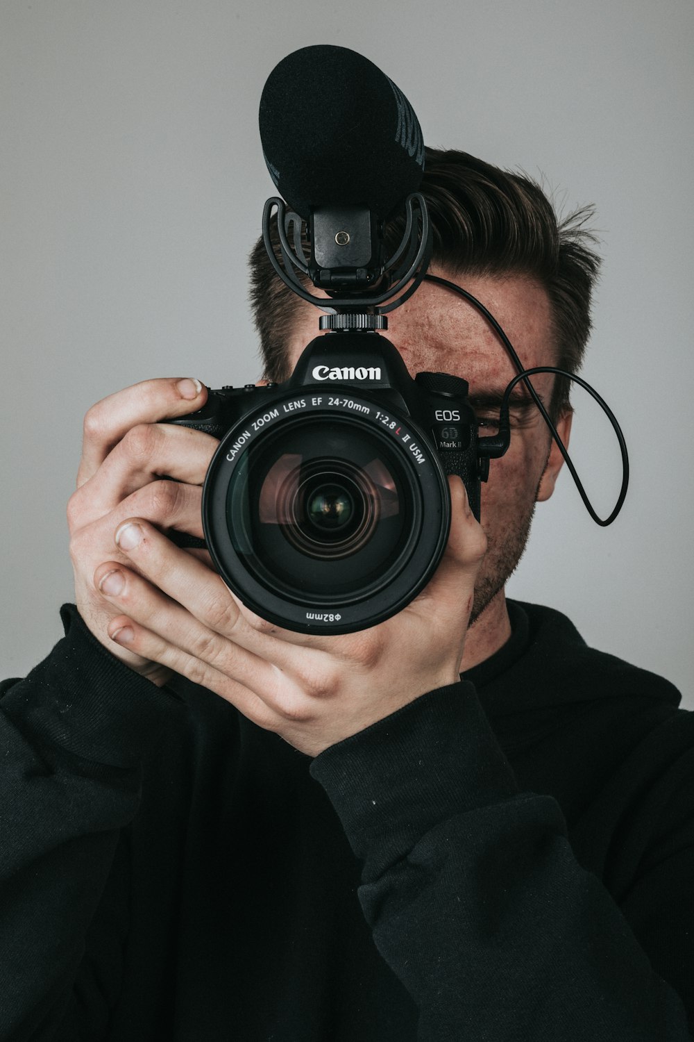 man in black long sleeve shirt holding black nikon dslr camera