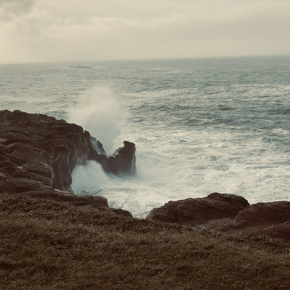 ocean waves crashing on brown rock formation during daytime