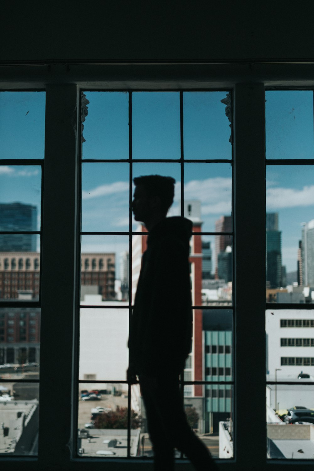 silhouette of man standing in front of window