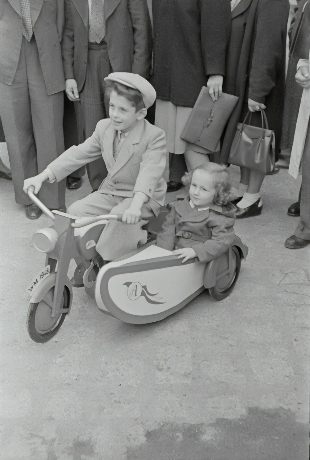 foto em tons de cinza de crianças andando no triciclo