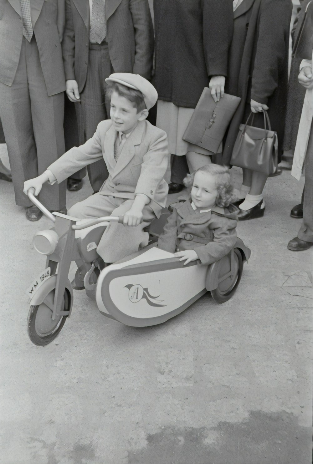 Photo en niveaux de gris d’enfants montant sur un tricycle