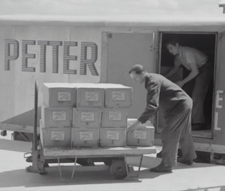 man in gray long sleeve shirt and pants standing beside cardboard boxes