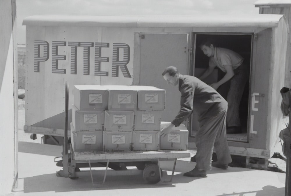 man in gray long sleeve shirt and pants standing beside cardboard boxes