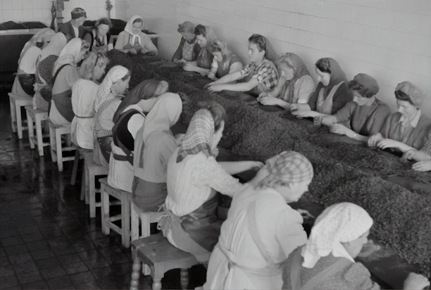 A group of women volunteers sorting donated clothes with smiles in a bright community center.