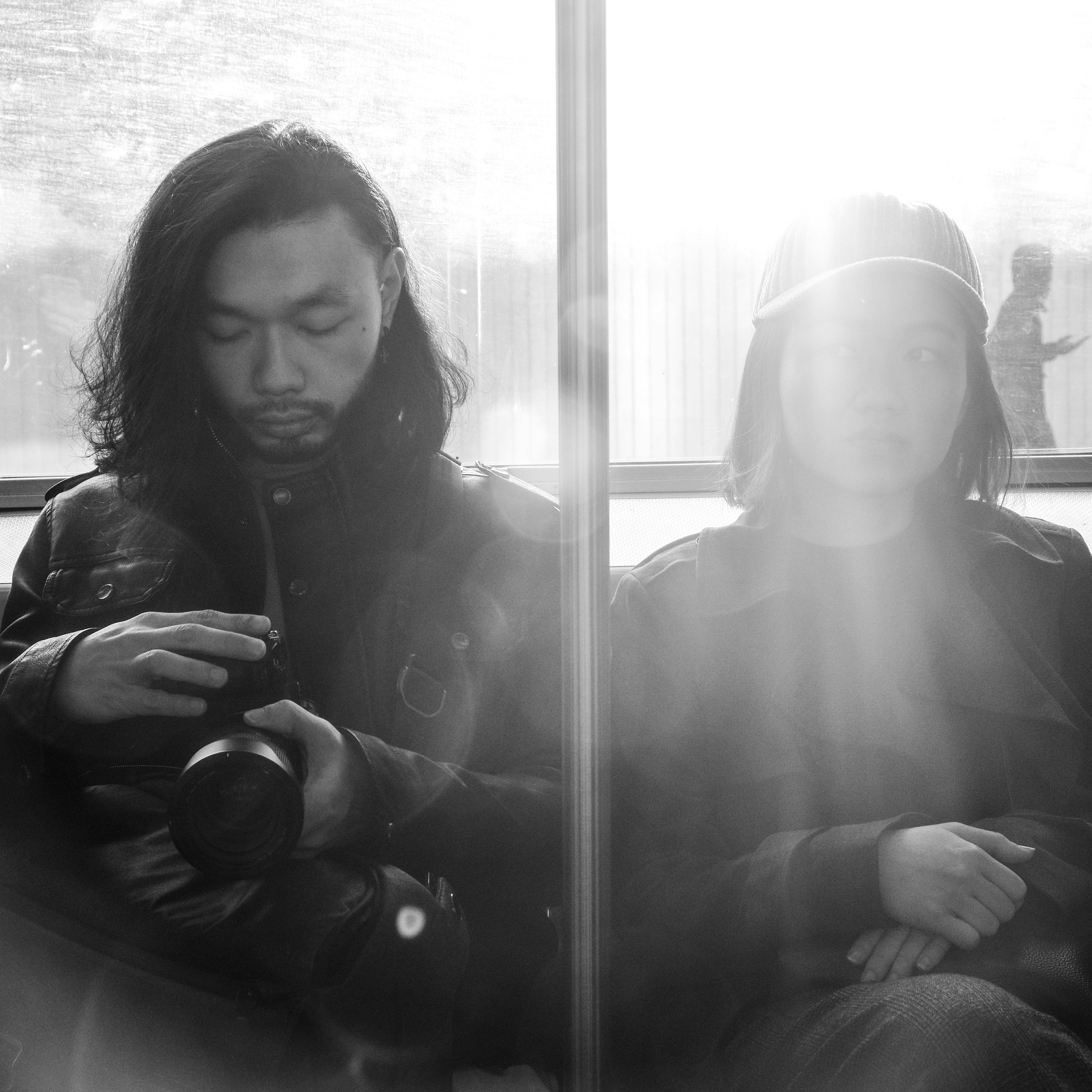 grayscale photo of woman and man sitting on the window