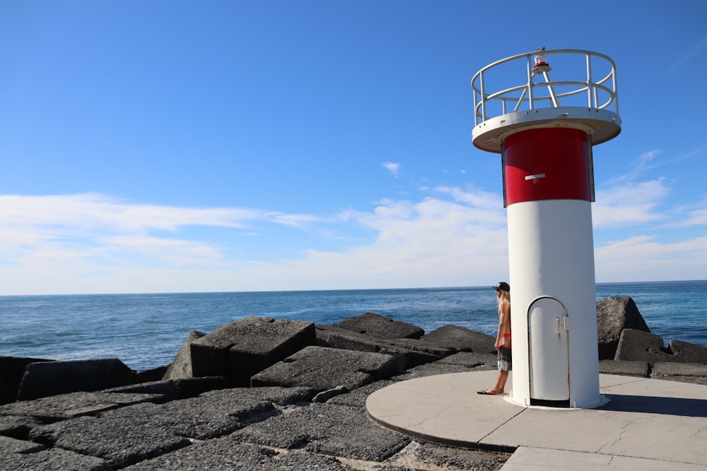 white and red lighthouse near body of water during daytime