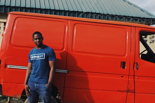 A confident tradie checking his phone with a satisfied smile, standing outside his local work van.