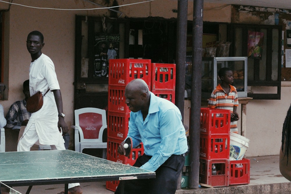 homme en chemise blanche et pantalon gris debout à côté d’une table