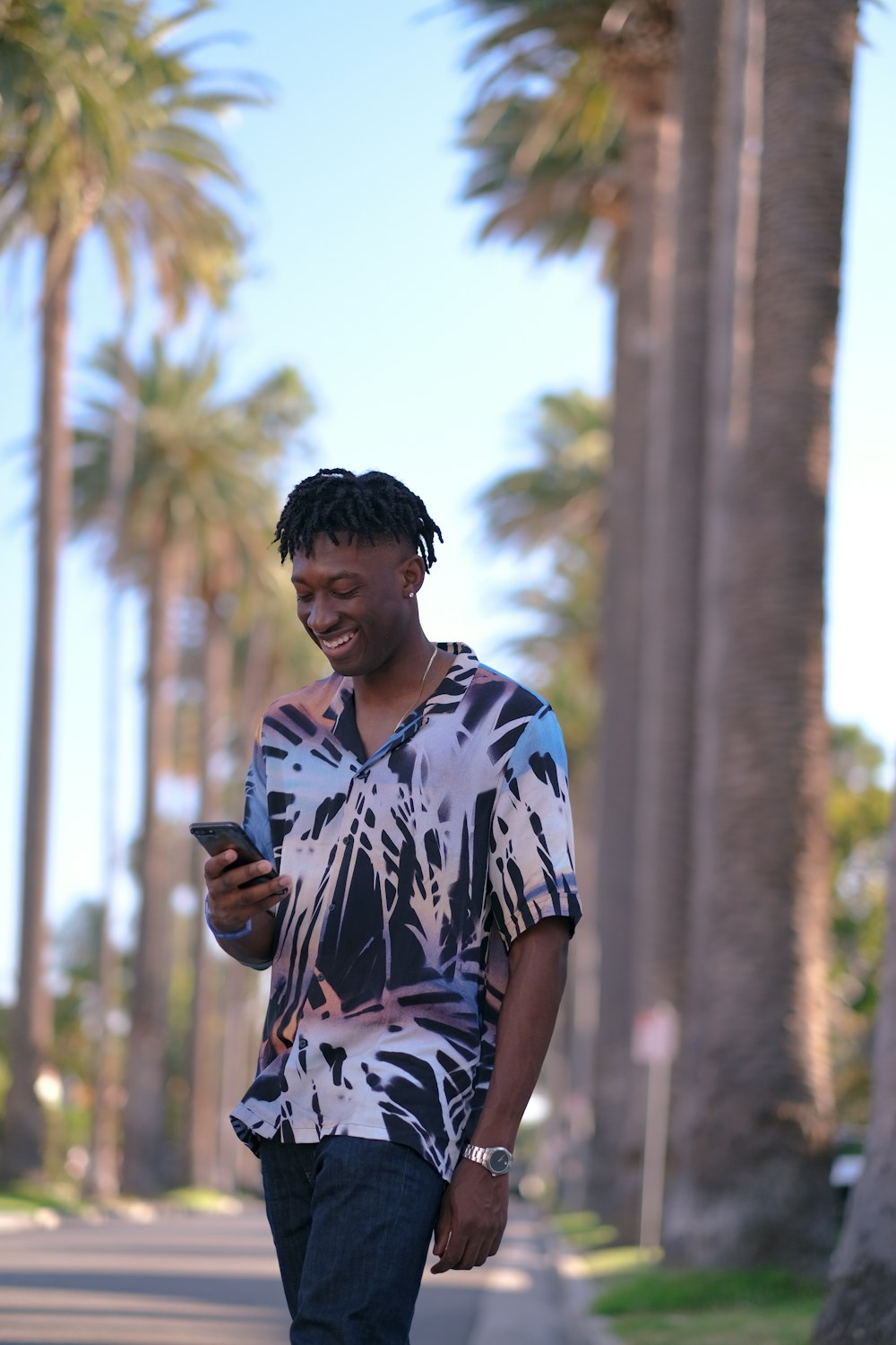 man in blue and white floral shirt holding black smartphone