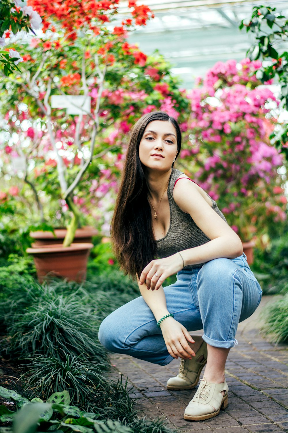 woman in gray tank top and blue denim jeans sitting on gray concrete floor