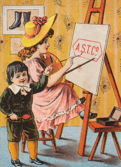 A vintage illustration of a young girl and boy engaging in an art activity. The girl, wearing a yellow hat and pink dress, is seated on a stool while painting on an easel. The boy, dressed in a dark suit with yellow socks, stands beside her holding a brush and pointing at the canvas. The easel displays the text 'A.S.T. Co'. The room's wallpaper features a floral pattern, and a small table next to them holds an open box. A framed artwork, depicting a pair of boots, hangs on the wall.