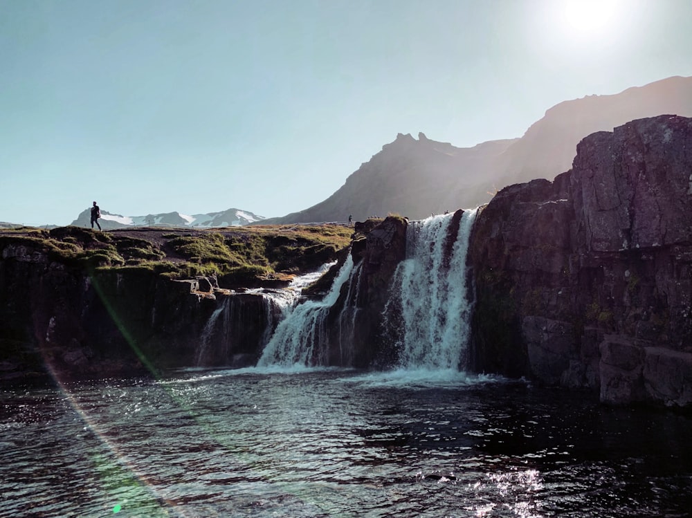 water falls near brown mountain during daytime