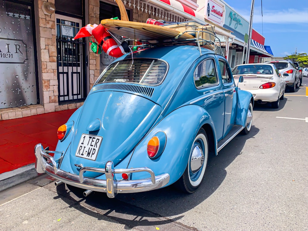 Volkswagen Beetle azul estacionado junto a un poste de madera marrón durante el día
