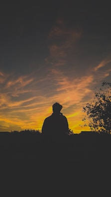 A silhouette of Douae against a colorful sunset sky.