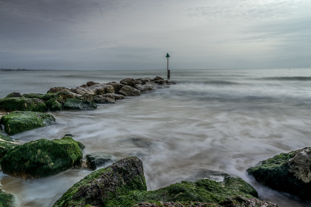 personne debout sur un rocher près de la mer pendant la journée