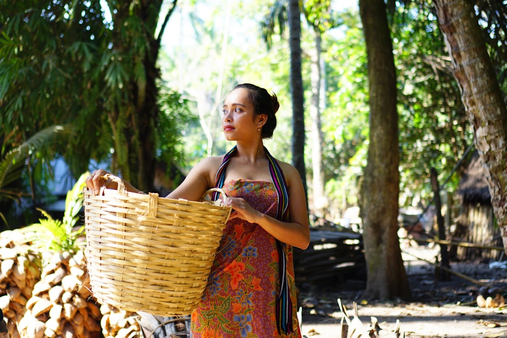 woman in red and yellow floral dress carrying brown woven basket