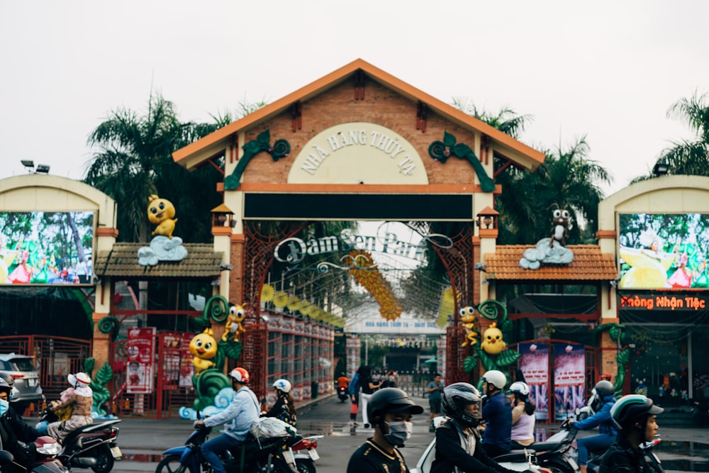 people riding motorcycle on road near brown wooden building during daytime