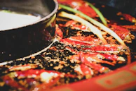 Close-up of a bubbling pot of fragrant Tom Yum soup with fresh herbs floating on top.