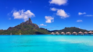 green mountain beside body of water under blue sky during daytime