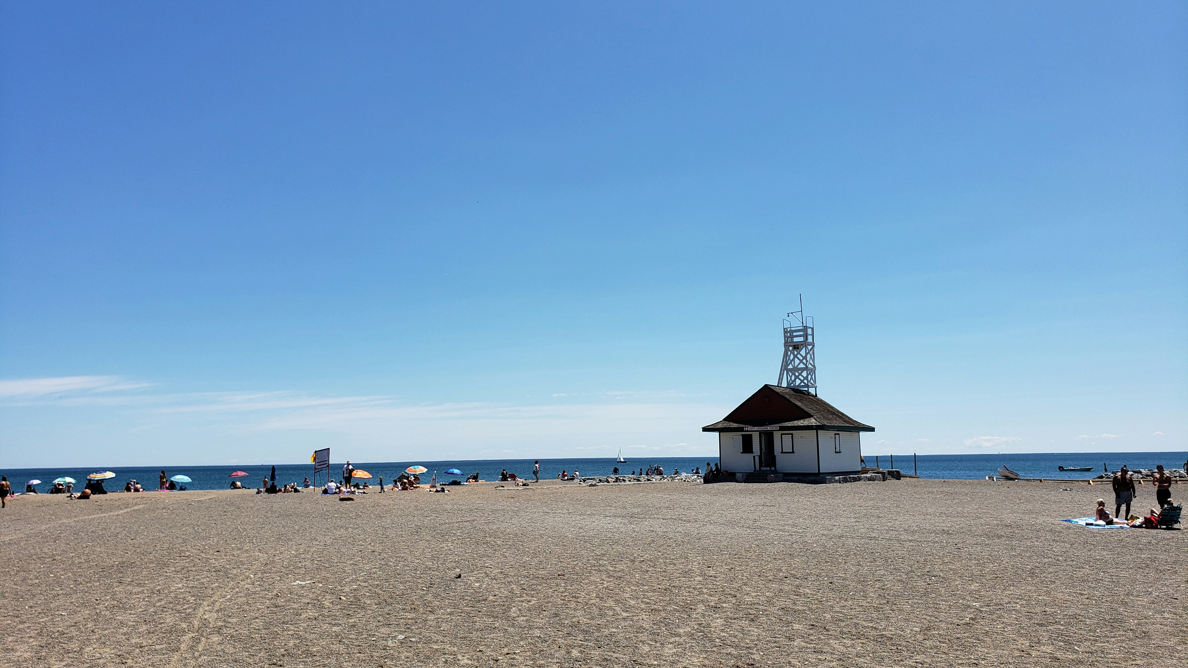People on the sand at Woodbine Beach beside Lake Ontario on a sunny day