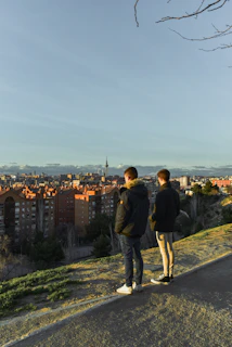 A couple enjoying a scenic sunset from a hilltop overlooking a vibrant cityscape.
