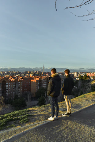 A couple enjoying a scenic sunset from a hilltop overlooking a vibrant cityscape.