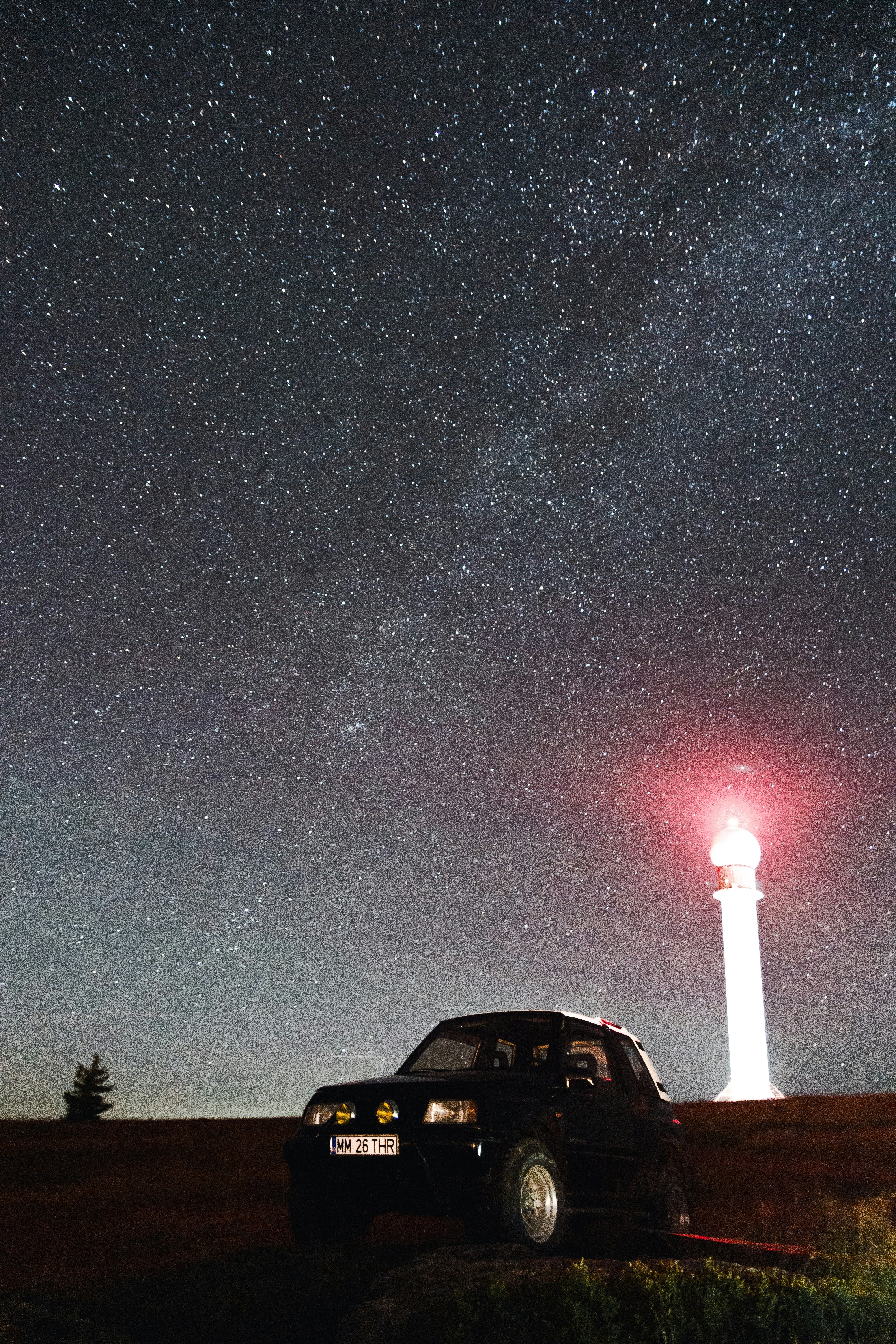 black car near red light post under starry night