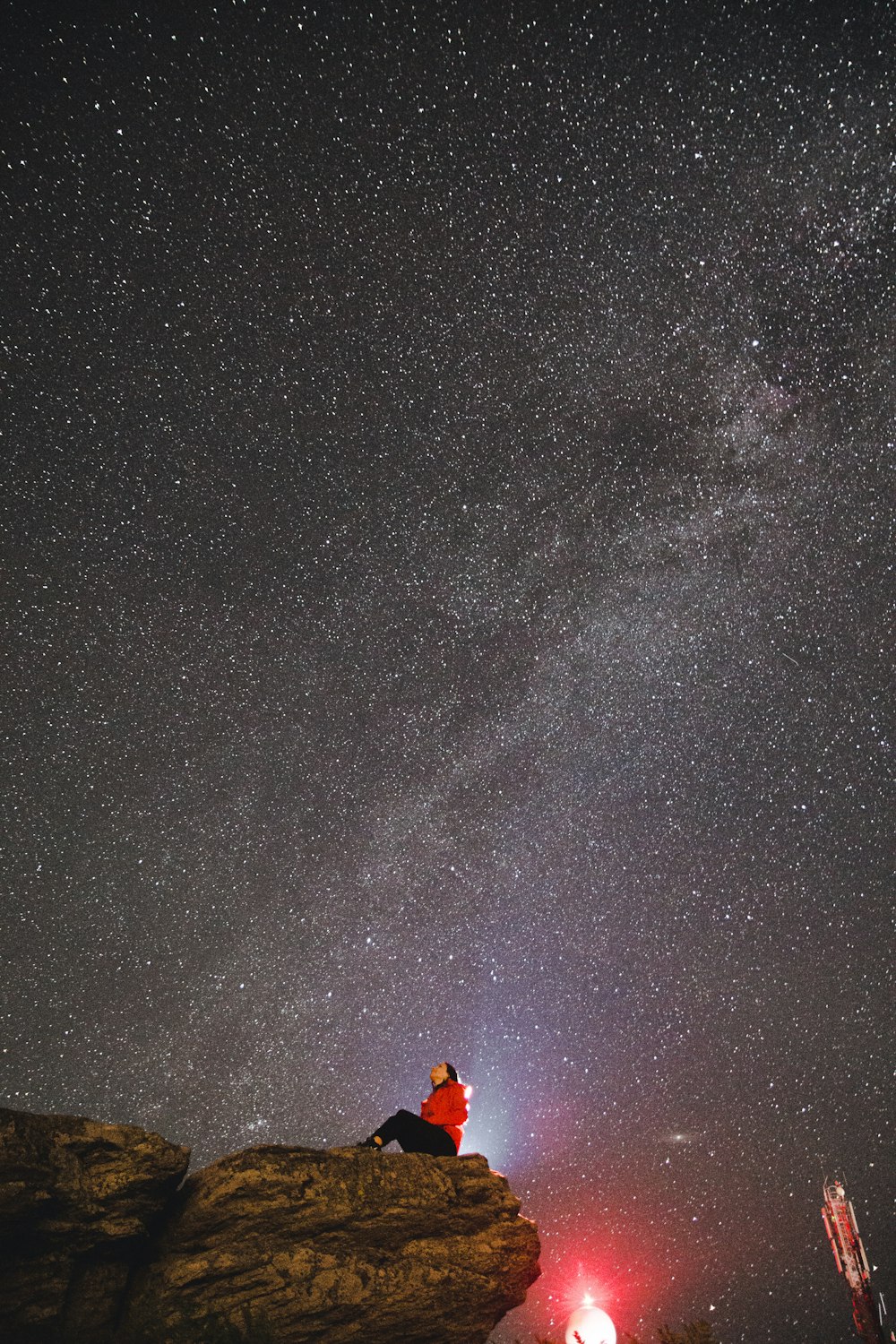 pessoa em jaqueta laranja em pé no chão marrom sob a noite estrelada