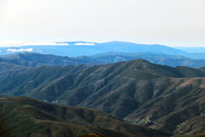A wide angle view of a wind turbine farm with rolling green hills.