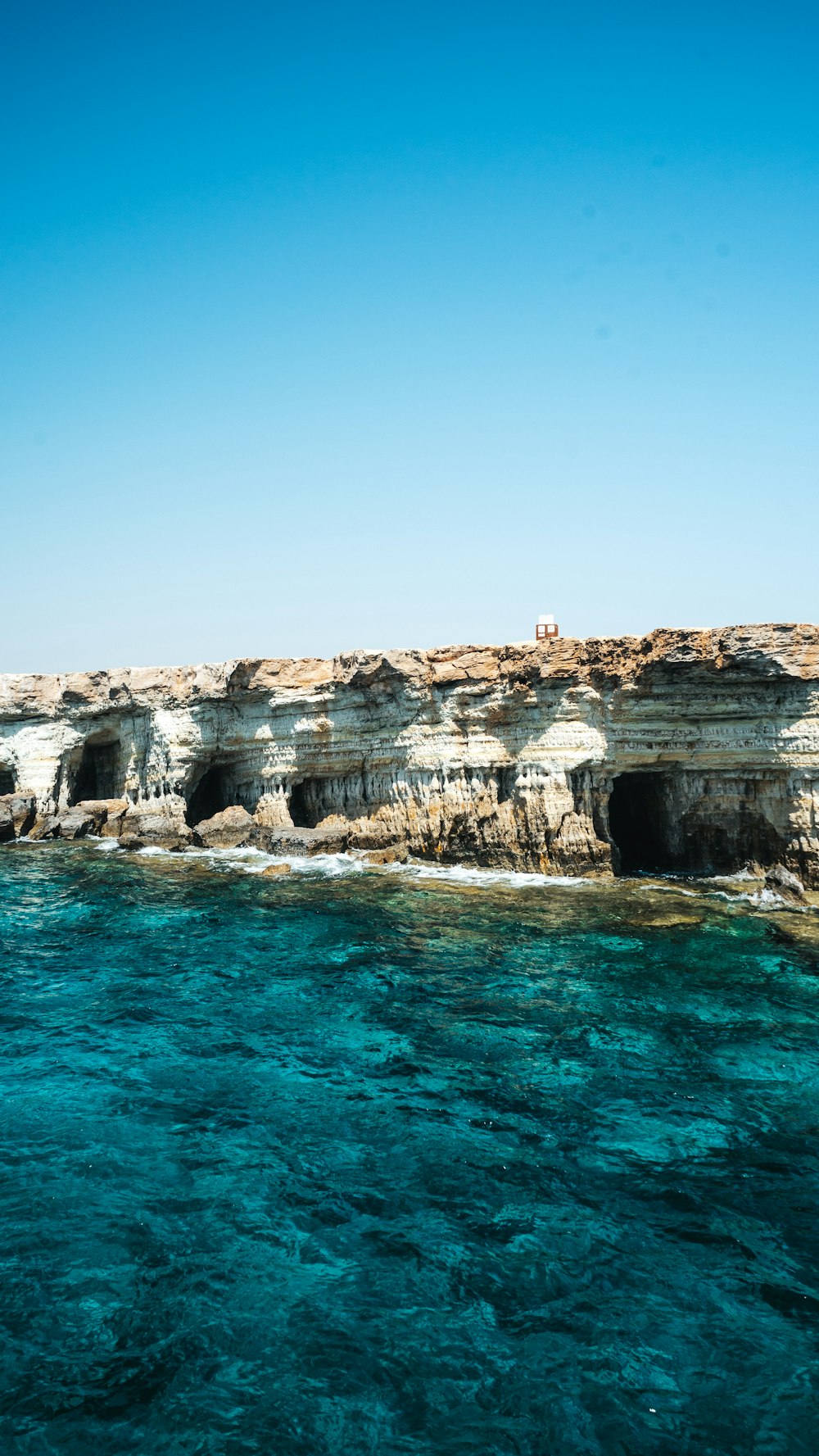 brown rock formation on blue sea under blue sky during daytime