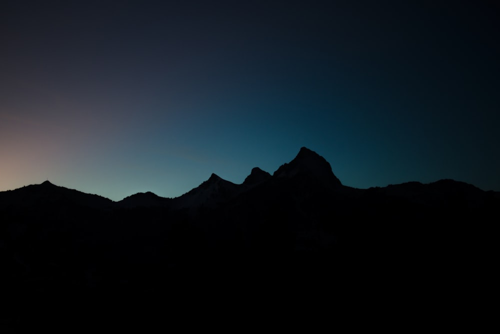 silhouette of mountain under blue sky during night time