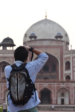 man in white long sleeve shirt taking photo of white dome building during daytime