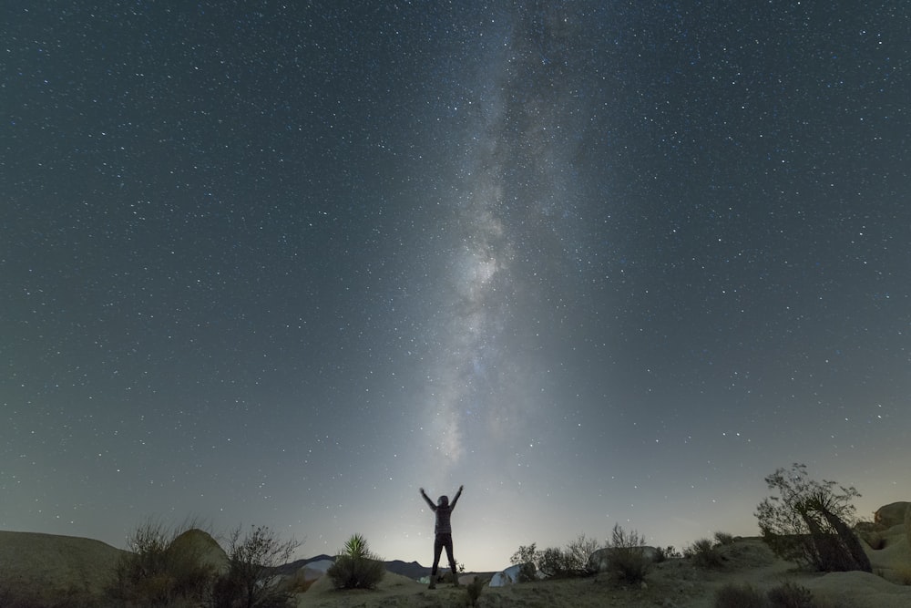 man standing on brown field under blue sky during night time