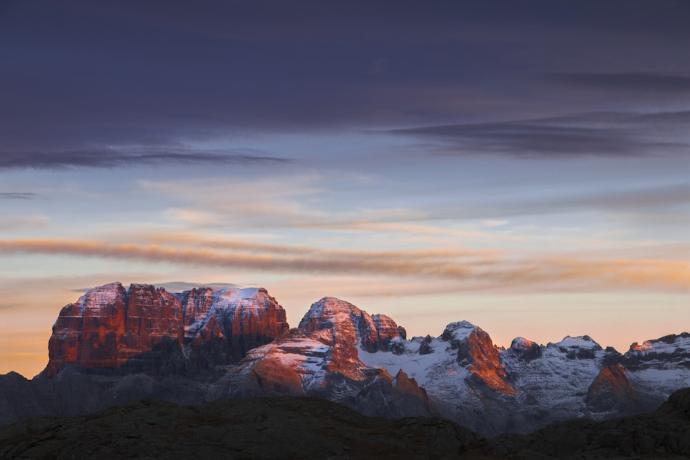 Une chaîne de montagnes couverte de neige sous un ciel nuageux