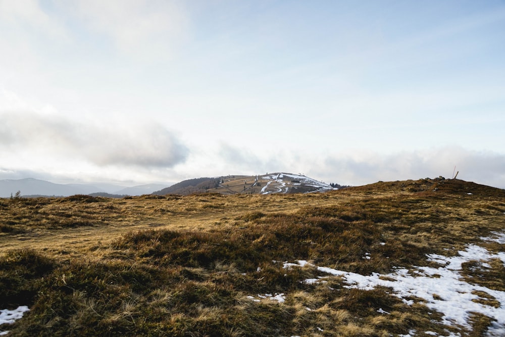 green grass field near mountain under white sky during daytime