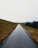gray asphalt road between green grass field during daytime