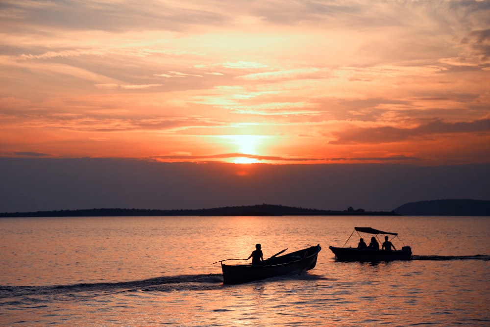silhueta de 2 pessoas andando no barco durante o pôr do sol
