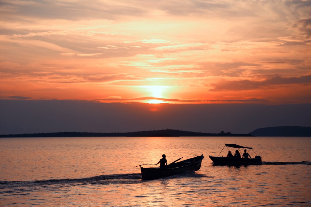 silhouette of 2 people riding on boat during sunset